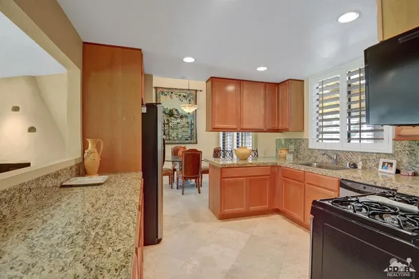 a kitchen with granite countertop a refrigerator stove top oven and sink
