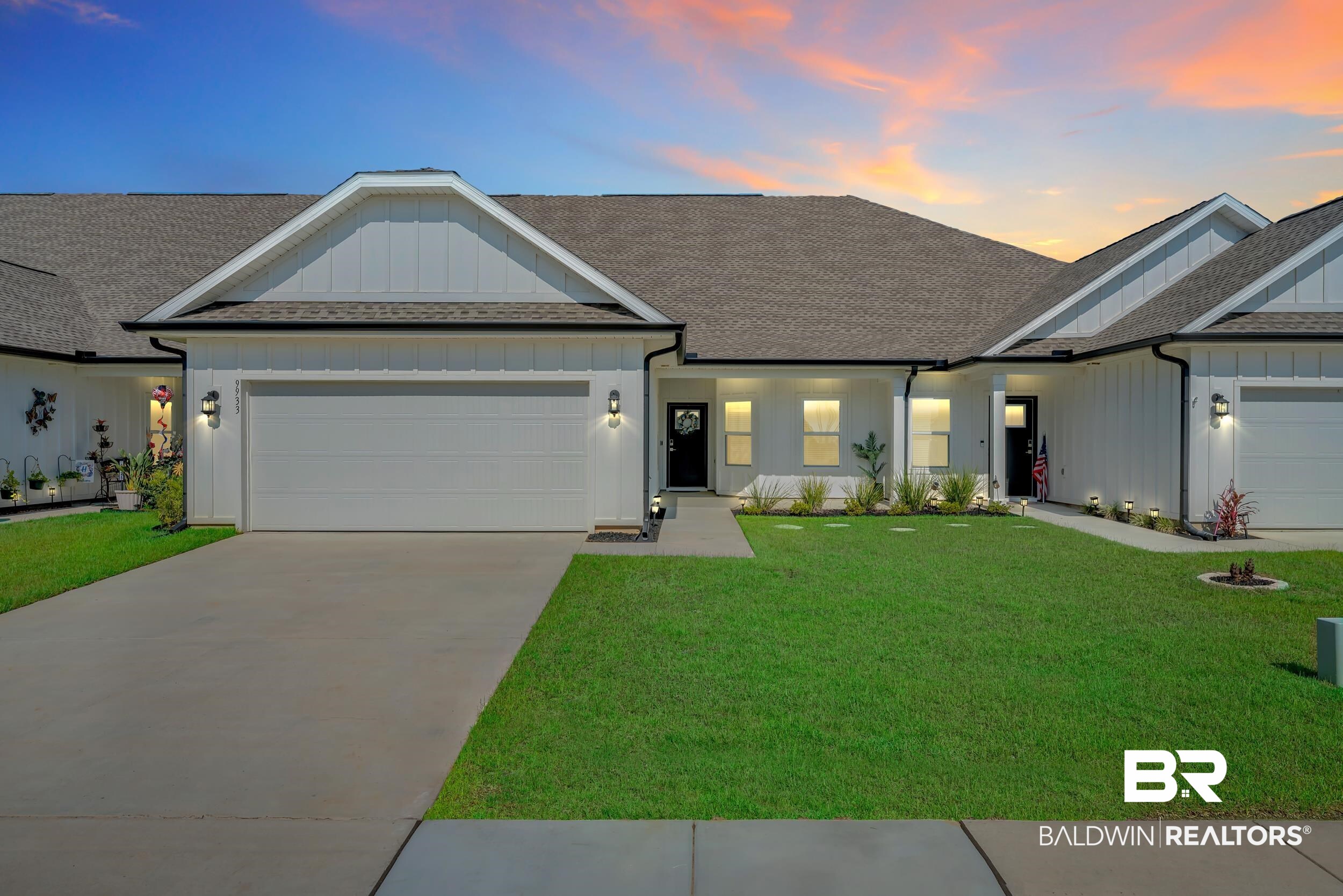 9933 Weller Cove Foley, AL 36535 - Photo 1 of 36 Contemporary white siding exterior featuring a dark asphalt shingle roof, integrated garage, concrete driveway, and a manicured lawn with landscape lighting