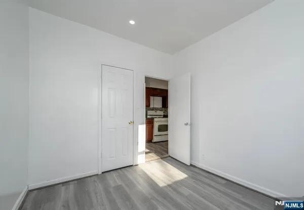a view of an empty room with wooden floor and closet