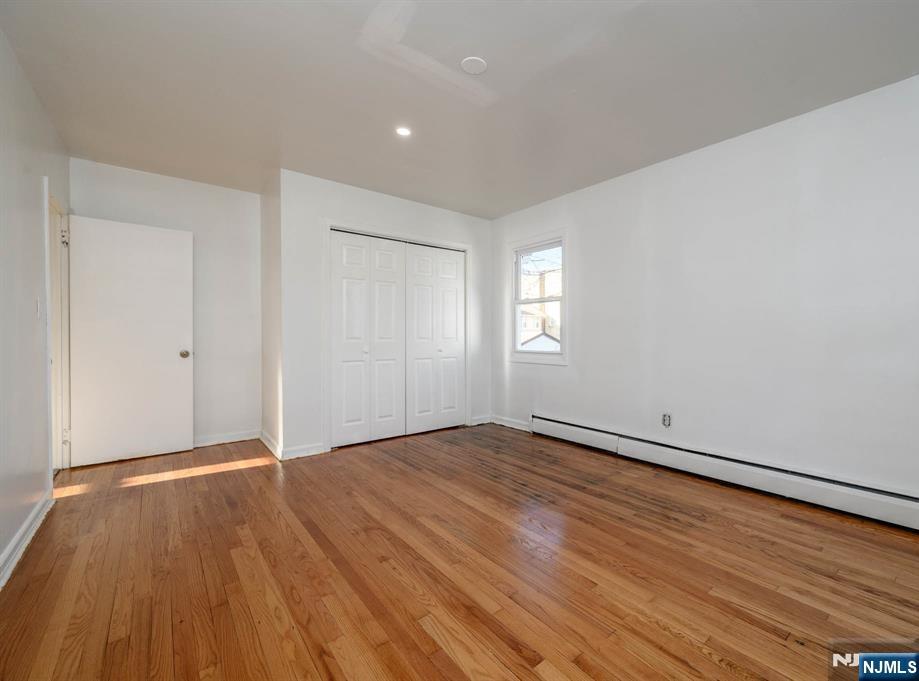 49 River Street, Unit 2 Lodi, NJ 07644 - Photo 19 of 24 an empty room with wooden floor and windows