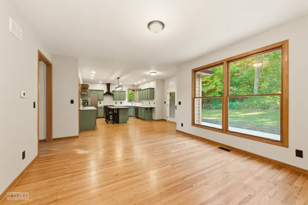 a view of an empty room with kitchen view and a window