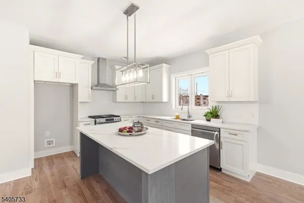 a kitchen with a stove a sink dishwasher and a refrigerator with wooden floor