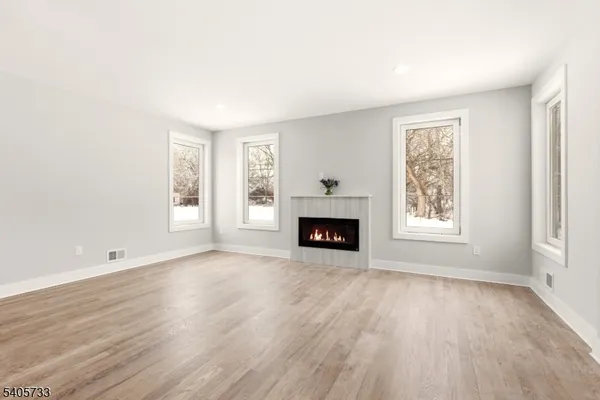 an empty room with windows and fireplace