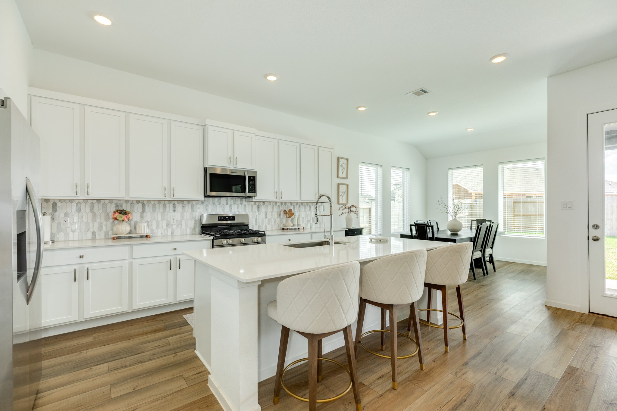2618 Jasper Oaks Drive Rosharon, TX 77583 - Photo 13 of 43 a kitchen with a dining table chairs and white cabinets