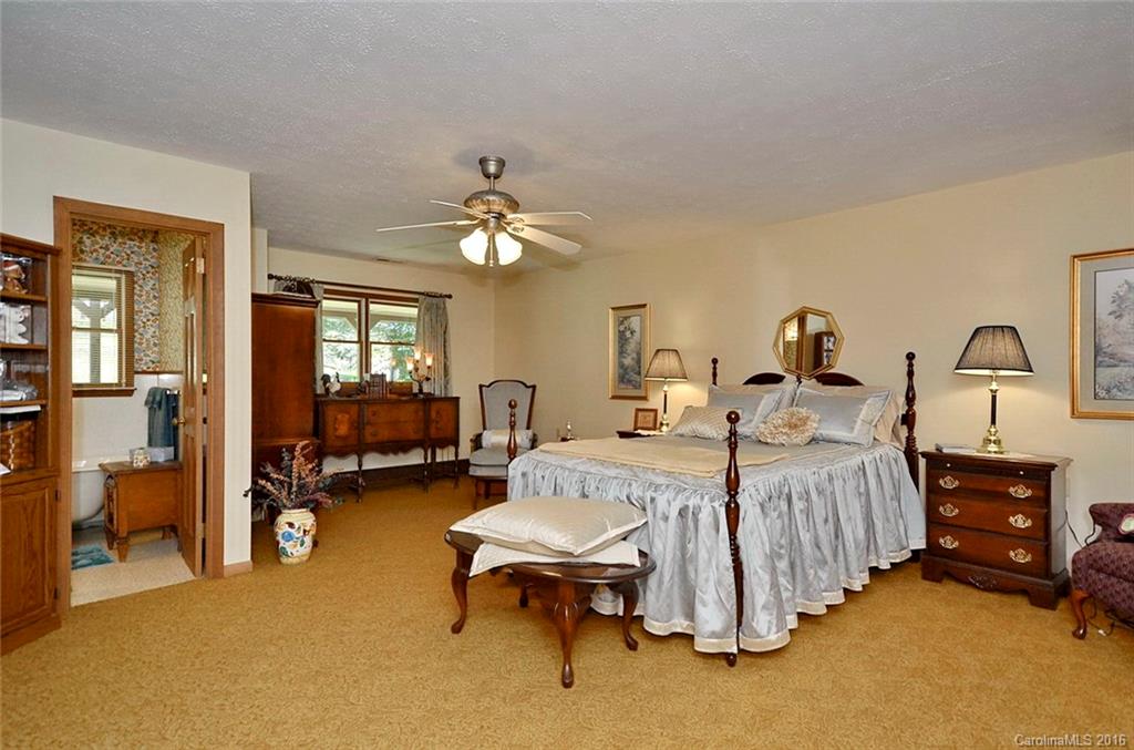 110-114 Hilltop Road Waynesville, NC 28786 - Photo 14 of 21 a spacious bedroom with a bed and a chandelier