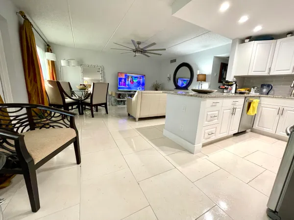 a view of living room kitchen with stainless steel appliances granite countertop furniture and a window