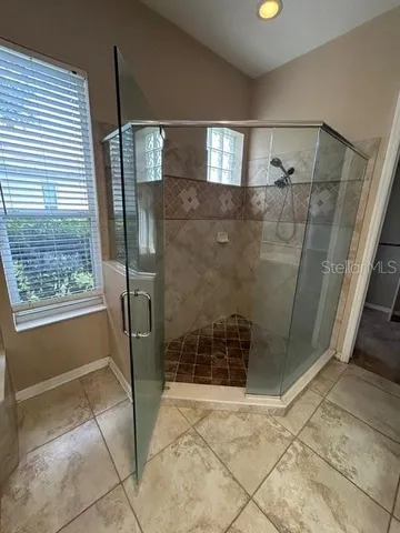 a bathroom with a glass shower door and a window