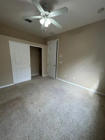 an empty room with a ceiling fan and a window