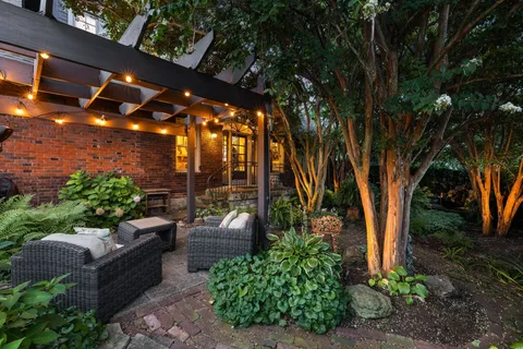 a view of a patio with couches and table and chairs with wooden fence and plants