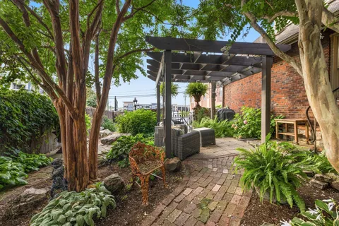 a view of a patio with table and chairs potted plants and large tree