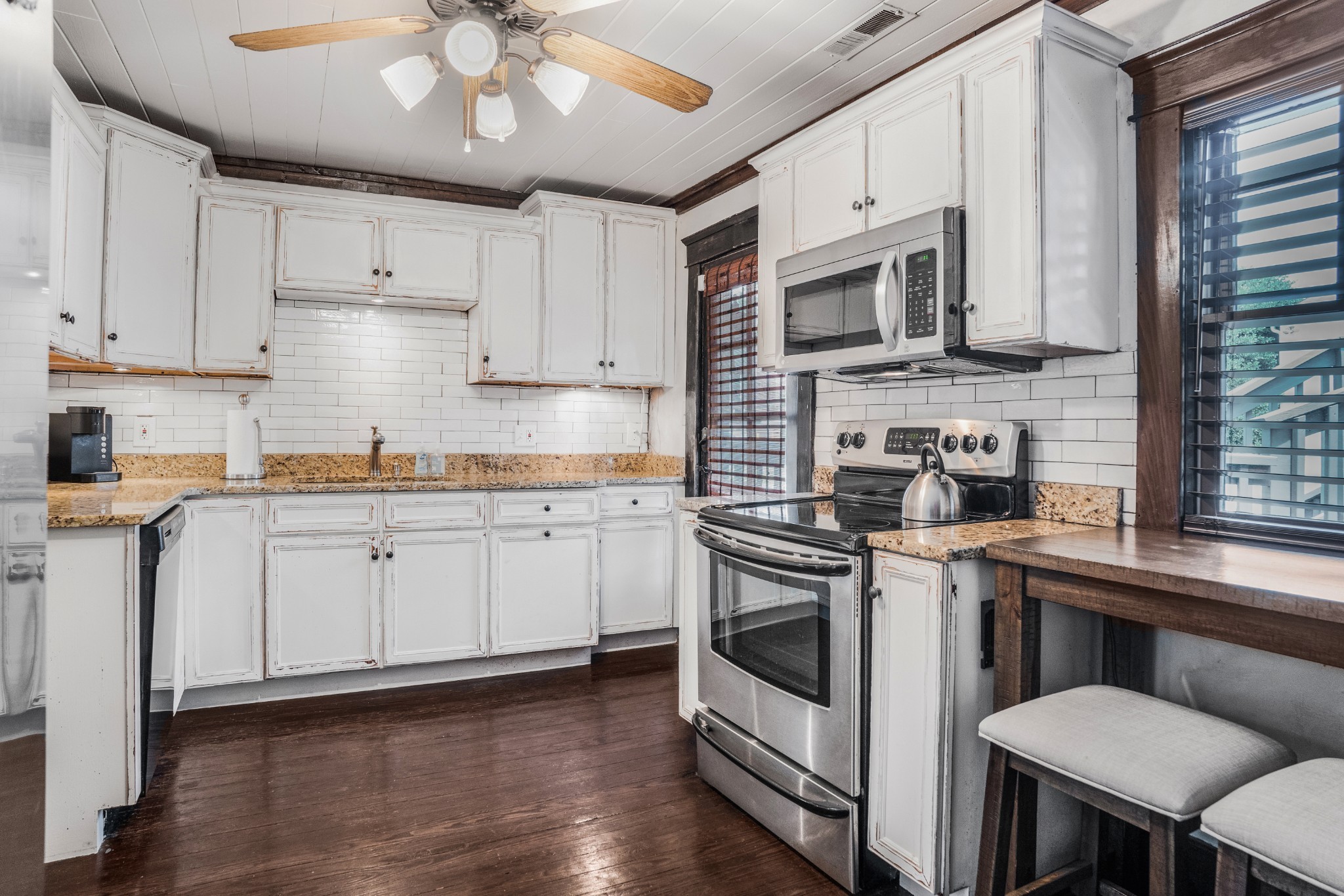 707 Inverness Avenue Nashville, TN 37204 - Photo 31 of 45 a kitchen with stainless steel appliances white cabinets a sink a stove a refrigerator and microwave with wooden floor
