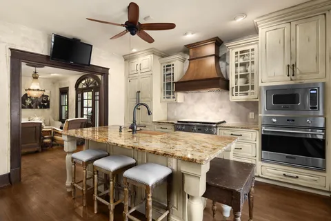 a kitchen with stainless steel appliances granite countertop a stove top oven a sink a dining table and chairs with wooden floor