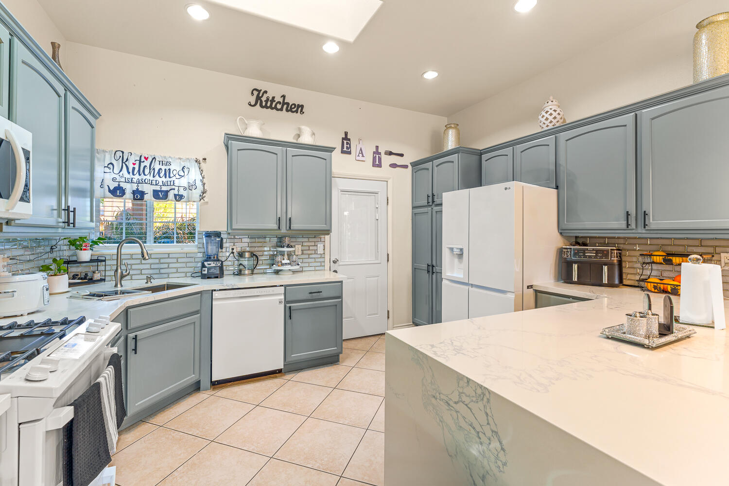 67305 Medano Road Cathedral City, CA 92234 - Photo 3 of 37 a kitchen with a sink a refrigerator and white cabinets