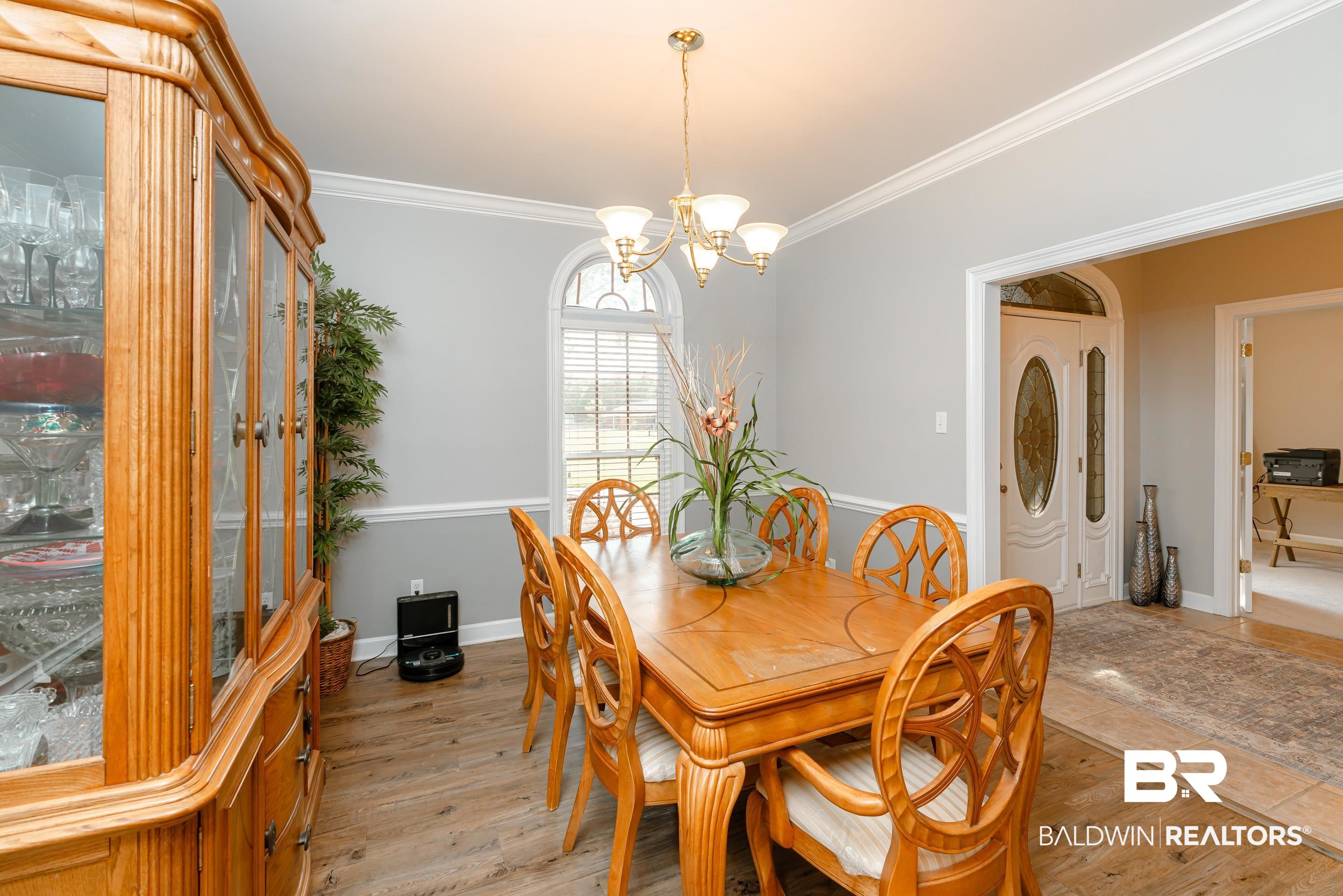 9477 Deerfield Drive Irvington, AL 36544 - Photo 16 of 58 Dining space with crown molding, light hardwood / wood-style flooring, and an inviting chandelier