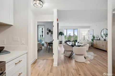 a living room with couches chairs and kitchen view with wooden floor