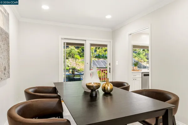 a kitchen with stainless steel appliances a dining table chairs stove refrigerator and cabinets