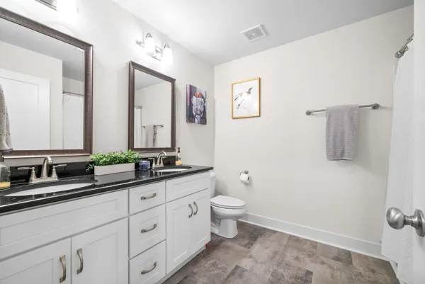 a bathroom with double vanity a toilet a and mirror