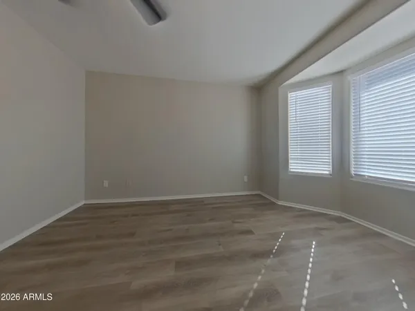 an empty room with wooden floor chandelier fan and windows
