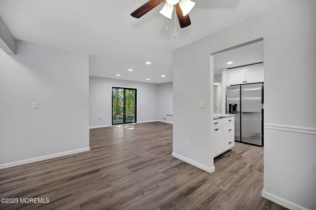 a view of kitchen and empty room with wooden floor