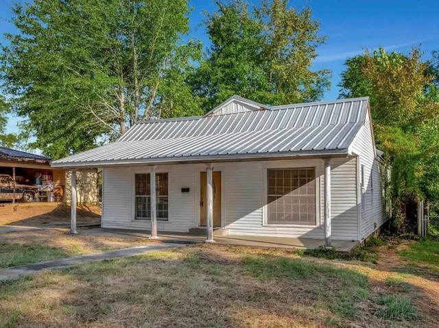 a view of a house with a yard and large tree