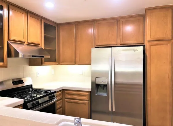 a kitchen with granite countertop a refrigerator and a stove top oven