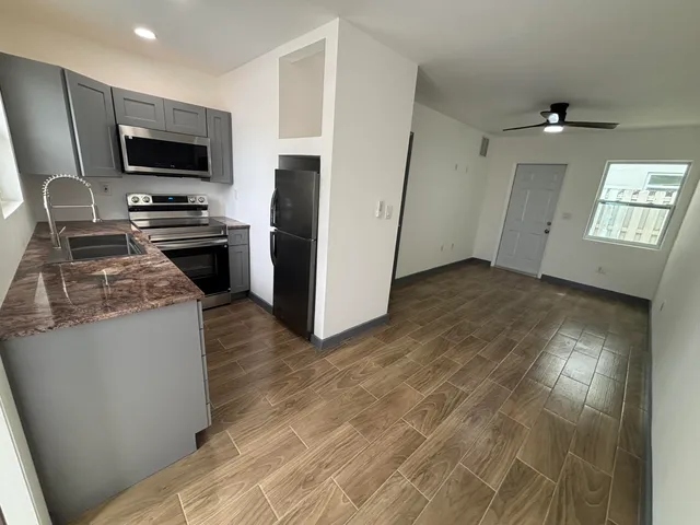 a kitchen with granite countertop a refrigerator stove and microwave