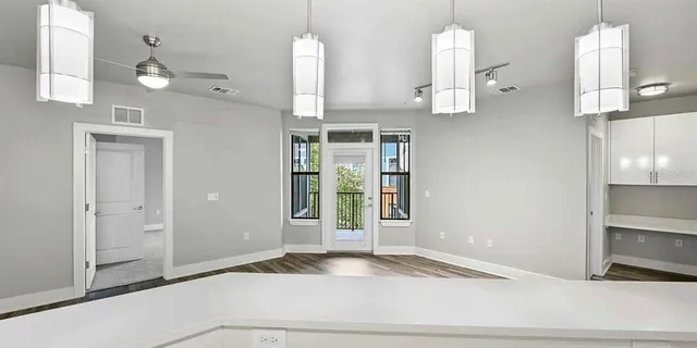 a view of a kitchen with kitchen island a sink wooden floor and stainless steel appliances