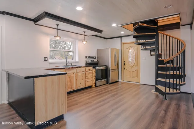 a kitchen with stainless steel appliances a refrigerator and a wooden floor