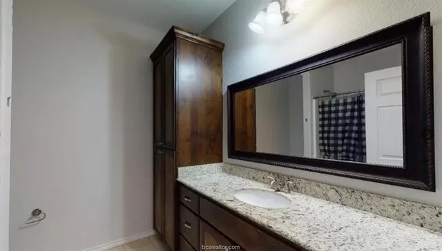 a bathroom with a granite countertop sink and a mirror