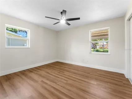 a view of an empty room with wooden floor and a window