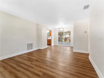 a view of an empty room with window and wooden floor