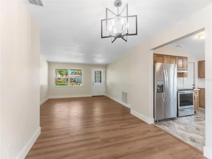 an empty room with wooden floor chandelier and windows
