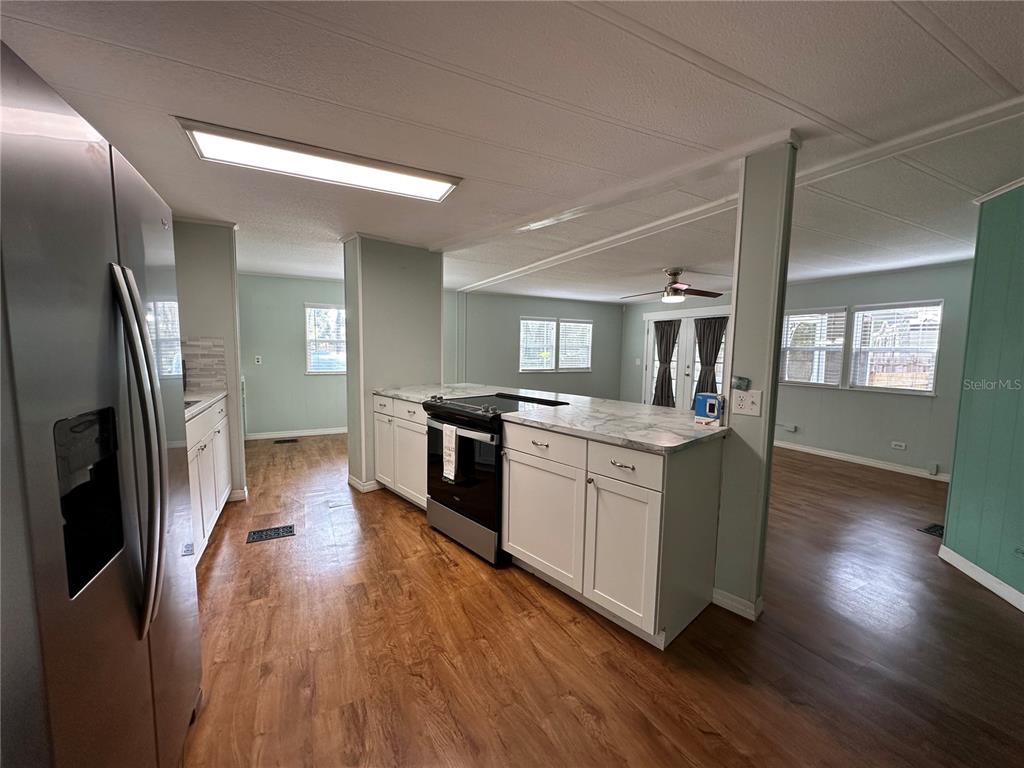 24007 River Road Astor, FL 32102 - Photo 4 of 37 a kitchen with stainless steel appliances kitchen island granite countertop a stove a refrigerator a sink a oven with wooden floor and cabinets