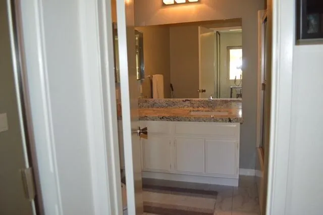 a bathroom with a granite countertop sink and a mirror