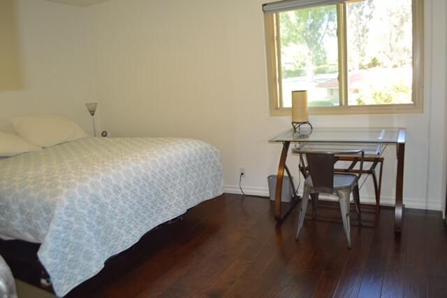 a bedroom with a bed and a table with wooden floor