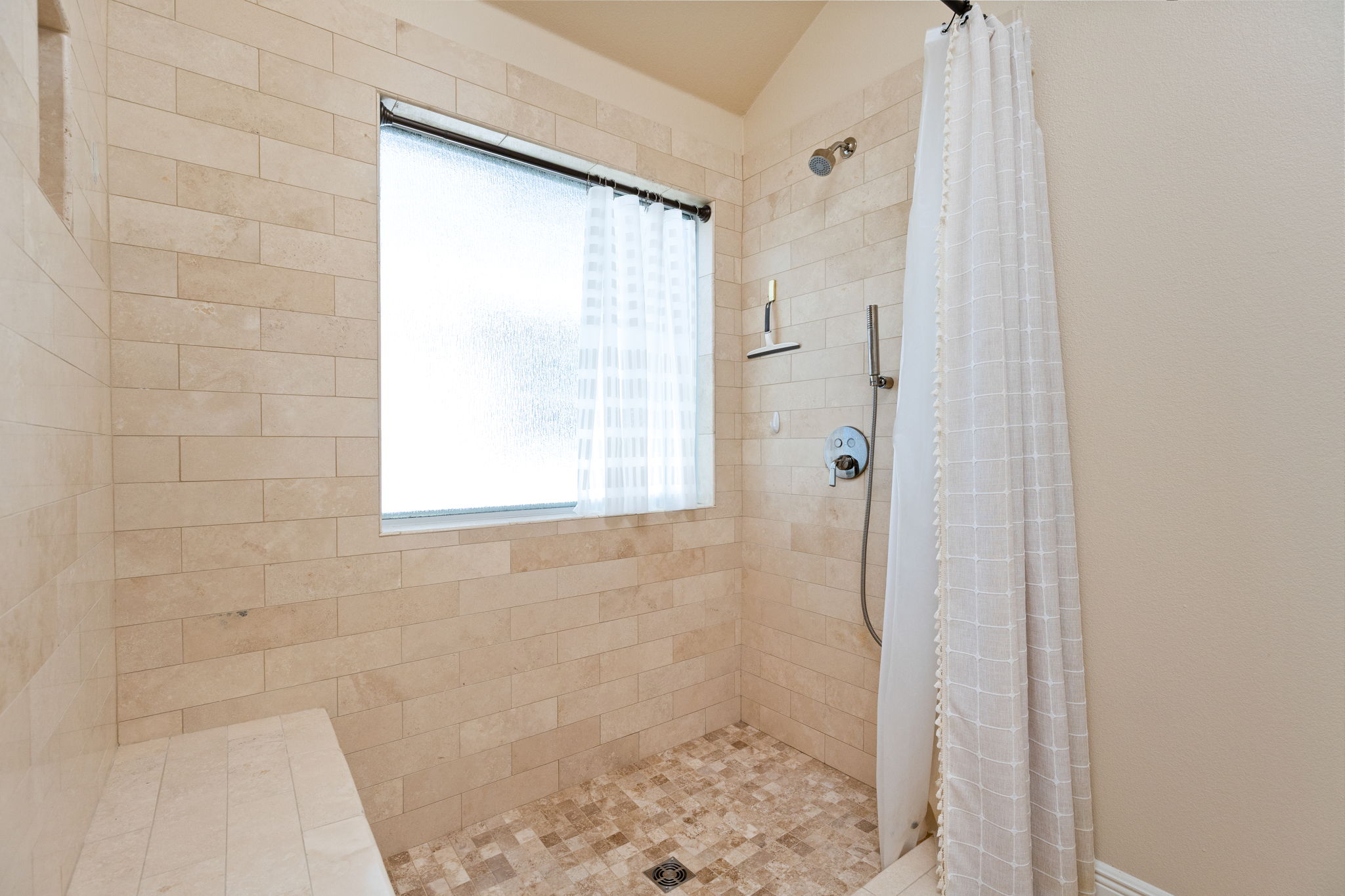 784 Sampson Kyle, TX 78640 - Photo 15 of 40 A walk-in shower features tiled walls, a built-in bench, and a privacy glass window.
