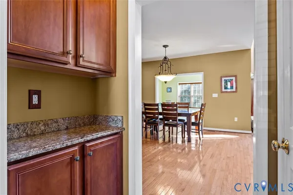 a kitchen with granite countertop a table chairs a sink dishwasher stove and cabinets with wooden floor