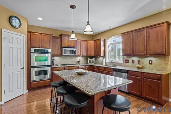 a kitchen with stainless steel appliances granite countertop a kitchen island a refrigerator a stove a dining table and chairs