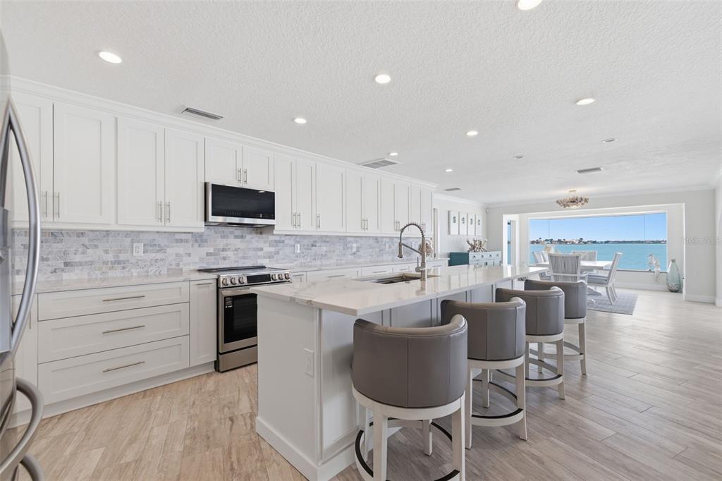 16123 6th Street East Redington Beach, FL 33708 - Photo 11 of 48 a large kitchen with kitchen island a island a stove a cabinets and a dining table with wooden floor