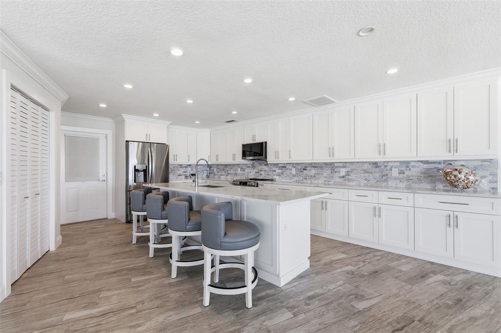 16123 6th Street East Redington Beach, FL 33708 - Photo 12 of 48 a kitchen with stainless steel appliances granite countertop a table chairs sink refrigerator and cabinets