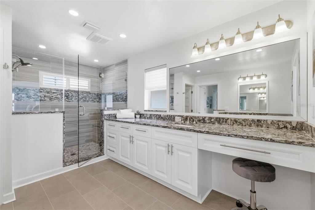 16123 6th Street East Redington Beach, FL 33708 - Photo 17 of 48 a bathroom with a granite countertop sink a large mirror and shower