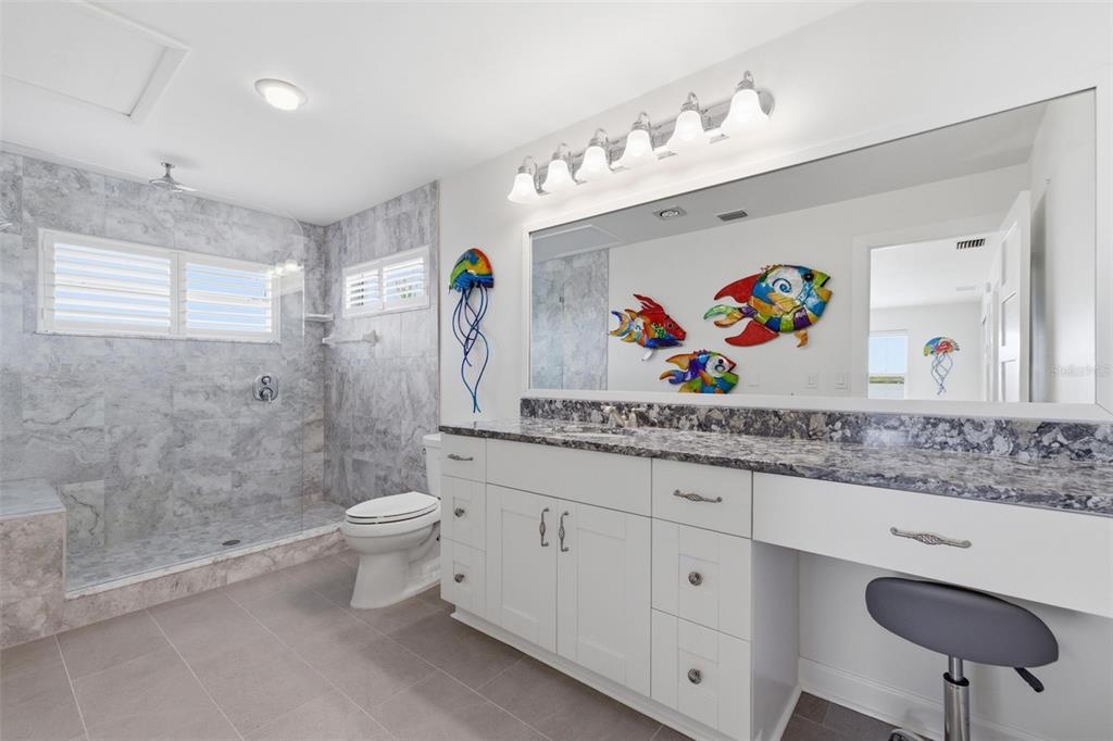 16123 6th Street East Redington Beach, FL 33708 - Photo 27 of 48 a bathroom with a granite countertop sink a toilet and a shower