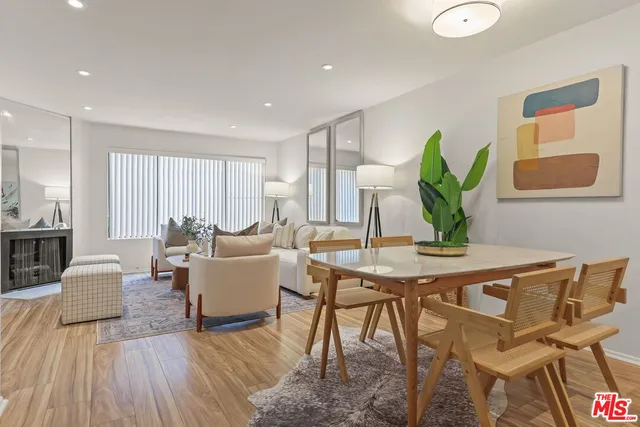 a living room with furniture a potted plant and open kitchen view
