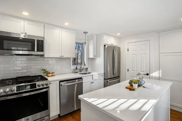 a kitchen with stainless steel appliances a stove a sink a microwave a refrigerator and cabinets