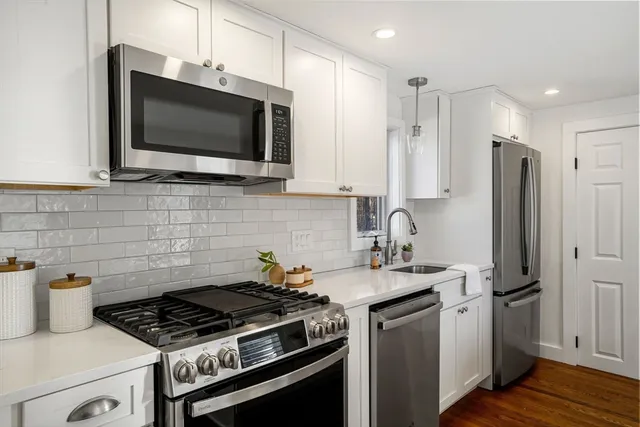 a kitchen with stainless steel appliances a sink a stove a microwave cabinets and a wooden floor