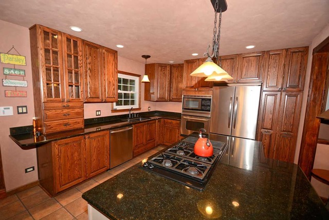 318 Village Road Willowbrook, IL 60527 - Photo 10 of 23 a kitchen with stainless steel appliances granite countertop a refrigerator a stove and a sink with wooden floor