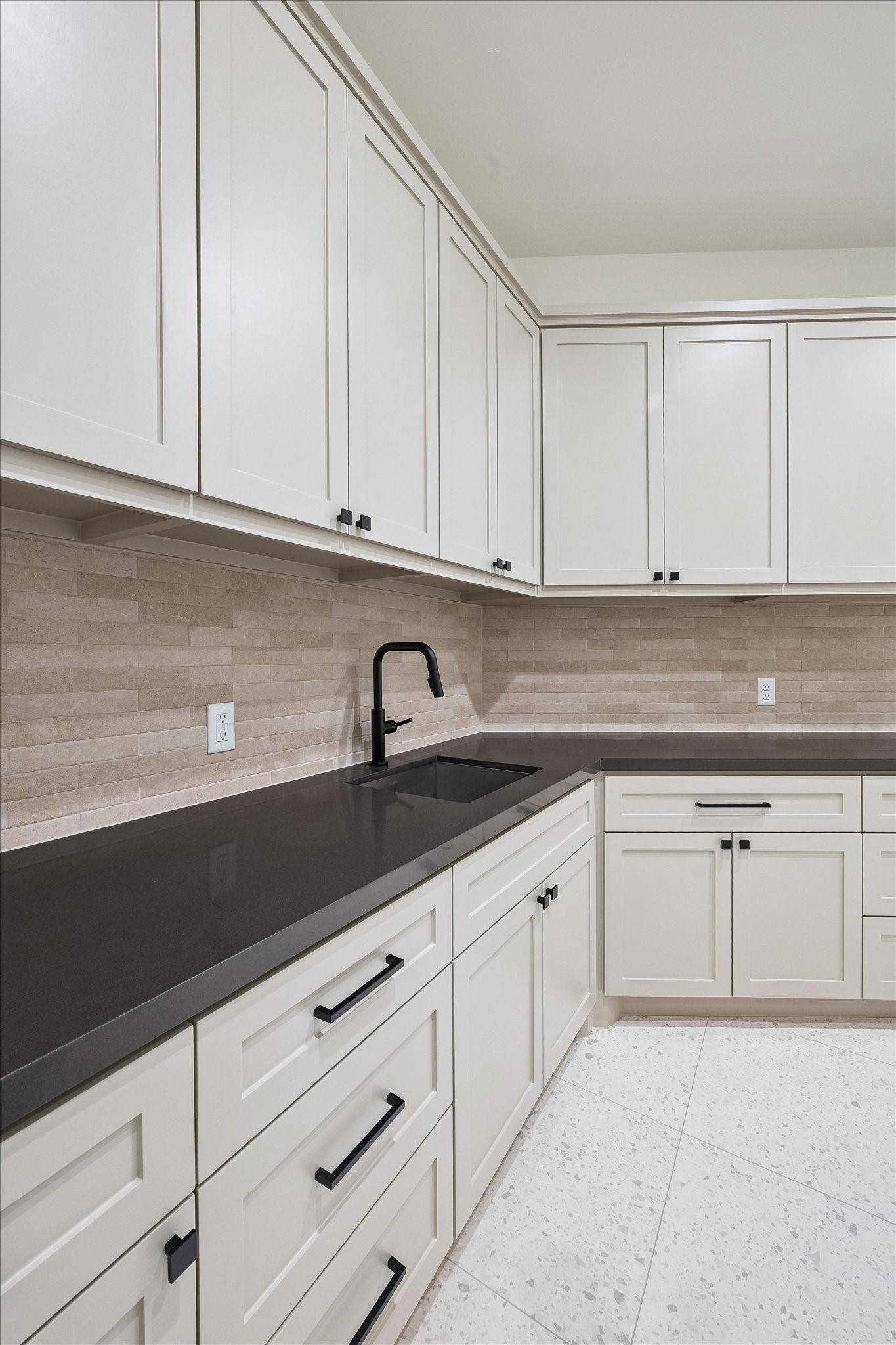 65 Shadow Creek Ridge Drive Spring, TX 77389 - Photo 25 of 41 Crisp cream toned shaker cabinetry, sleek dark countertops, and a modern matte-black faucet elevate this kitchen. cabinetry, stone-look counters, and a sleek tile backsplash.