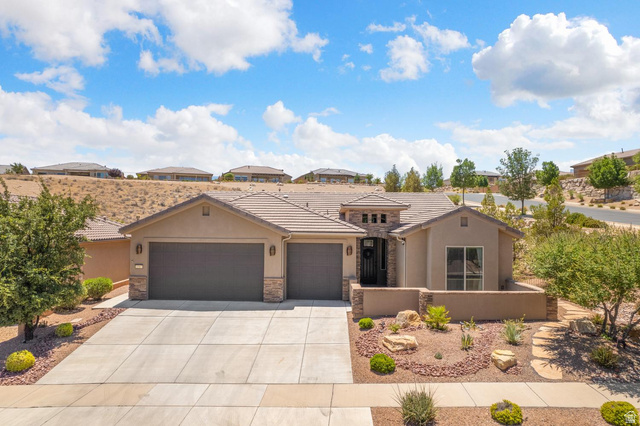 1587 Whitestone Drive St. George, UT 84790 - Photo 3 of 36 Contemporary stucco and stone-accented home featuring a concrete driveway, two-car garage, tile roof, and desert-style landscaping