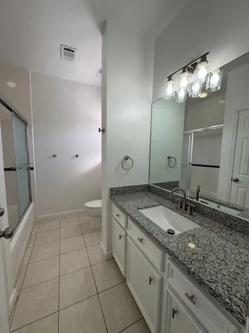 a bathroom with a granite countertop sink a toilet and a mirror