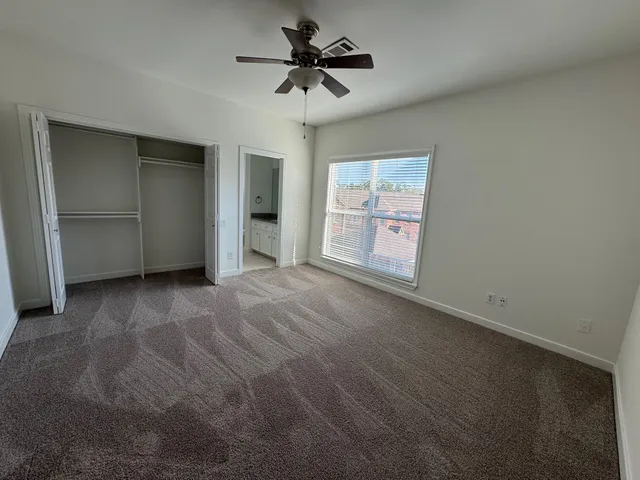 an empty room with windows and ceiling fan